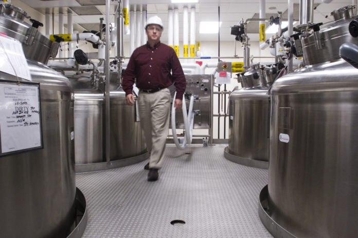 JIM RICH of Alexion Pharmaceuticals walks through an alley of buffer holding tanks at the Smithfield plant, which has been entirely renovated. / 