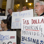 No money for ALCO, RI-WINs in ’08 BUSINESS LEADERS protest some of legislators' budget choices at a State House rally last week. /