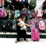 LOW TEMPERATURES and home prices continued to slow retail sales in June, the ICSC-UBS survey found. Above, Honorine Gautier holds her daughter, Bianca Gautier, 1, while shopping for a travel bag at a Target store in Miami.  / 