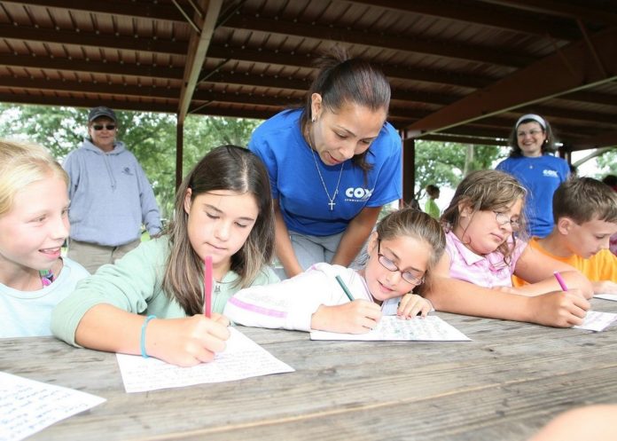 Cox’s Rosie Fernandez helps children at the Boys & Girls Clubs of Warwick write letters to the troops in Iraq as part of the company’s Random Acts of Kindness Day. Cox’s Rosie Fernandez helps children at the Boys & Girls Clubs of Warwick write letters to the troops in Iraq as part of the company’s Random Acts of Kindness Day.