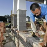 THE NORTHEAST, where housing starts surged 45.4 percent, was the only region to see no decline in September. Above, mason Luis Perez lays bricks on the front porch of a new house in Tallahassee, Fla., this Monday. / 