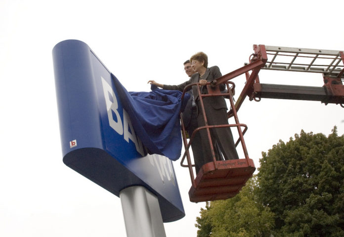 Bank Rhode Island opened its first new branch in two years last week. Above, BankRI president and CEO Merrill W. Sherman, right, and chief business officer James V. DeRentis get a lift in a cherrypicker as they prepare to unveil the new sign on Smithfield Avenue. / Bank Rhode Island opened its first new branch in two years last week. Above, BankRI president and CEO Merrill W. Sherman, right, and chief business officer James V. DeRentis get a lift in a cherrypicker as they prepare to unveil the new sign on Smithfield Avenue. /