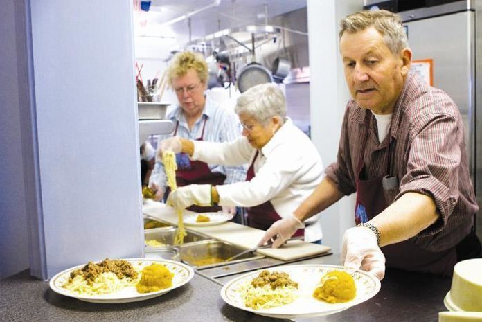 SERVING A HOT MEAL to the hungry are, from left, volunteers Ruth Newqueist, Mary La Plante and Jim McCaughey, 

at McCauley House in Providence. The charity struggles to meet an ever-growing demand for its services. / 