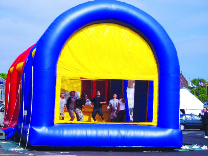 A CORPORATE GROUP takes part in a team-building exercise in an inflatable obstacle course at Fort Adams in Newport. / 