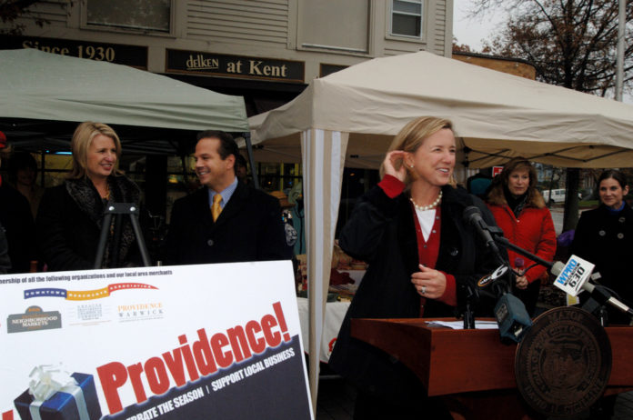 Wendy Brown, right, owner of Wendy Brown Linens, helps Providence Mayor David N. Cicilline, center, kick off the third annual Buy Providence holiday promotion. Joining the festivities at Wayland Square was Greater Providence Chamber of Commerce President Laurie White, left. / 