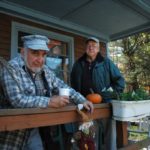 CLARK WHITFORD, right, whose son Jason runs the Blueberry Hill Store in Exeter, stands on the porch with customer Larry Fortin. / 