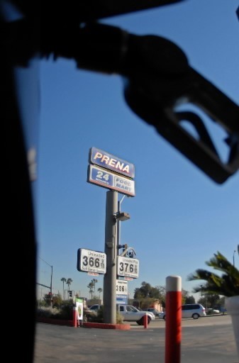 NATIONWIDE, the self-service price fell 6 cents to $3.009 per gallon for unleaded regular gasoline, AAA said. Above, a gas nozzle is silhouetted against the sky as a vehicle is fueled at Prena Food Mart in Torrance, Calif. / NATIONWIDE, the self-service price fell 6 cents to $3.009 per gallon for unleaded regular gasoline, AAA said. Above, a gas nozzle is silhouetted against the sky as a vehicle is fueled at Prena Food Mart in Torrance, Calif. /