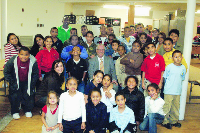 JWU PRESIDENT Irving Schneider and students Ellyn Gerrmann, to his left, and Donte Noble, at the back in green, are surrounded by children at South Providence Neighborhood Ministries. / 