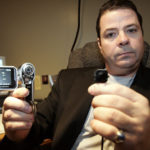 PRIVATE INVESTIGATOR Vic Pichette holds up a button cam, which is a small video camera hidden in a button that he uses while working in the field. The camera is just one of many new high-tech devices that investigators like Pichette use. / 