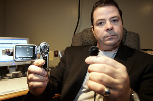 PRIVATE INVESTIGATOR Vic Pichette holds up a button cam, which is a small video camera hidden in a button that he uses while working in the field. The camera is just one of many new high-tech devices that investigators like Pichette use. / PRIVATE INVESTIGATOR Vic Pichette holds up a button cam, which is a small video camera hidden in a button that he uses while working in the field. The camera is just one of many new high-tech devices that investigators like Pichette use. /