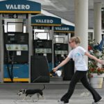 NATIONWIDE, the average price of self-serve unleaded rose 6 cents over the past week to $3.109, 9 cents more than in the Ocean State. Above, a woman walks her dog past a Valero station in Long Beach, Calif. / 