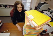 HOLLY SHADOIAN, director of admissions 
at Rhode Island College, sits behind a stack 
of applications. Most schools in the state have witnessed a spike in applications. / 