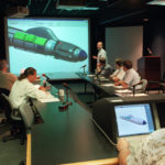 COME ON BOARD: A group of Electric Boat engineers and designers discuss advanced submarine concepts in one of the 
company’s Electronic Visualization Suites. The company said that it’s looking for 200 more people in both positions. / 