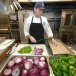 KEN BOWDISH, chef at McCoy Stadium, prepares kabobs of red onion, peppers and chicken for an upcoming game. Clam cakes and quesadillas are also on the menu. / 