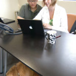 DIGICATION INC. owner Kelly Driscoll speaks with CEO Jeffrey Yen in her Providence office, while Roshi rests below. / 