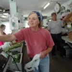 CINDY MORRIS weighs cucumbers for a customer at the Morris Farm vegetable stand. John Morris is on the right. / 