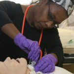HANDS-ON TRAINING: Anne Duré, of Providence, 
performs a tracheotomy on the SIM Man, a mannequin 
at CCRI. / 