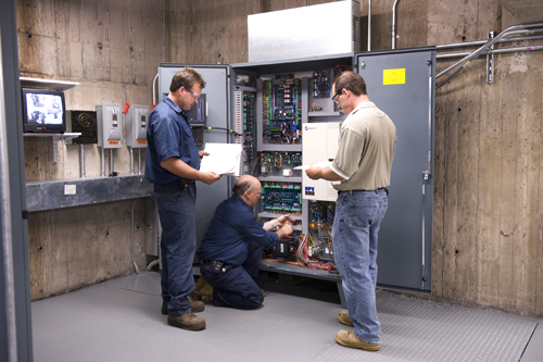 GOING UP: Atlantic Elevator South Company employees work on an elevator controller at Brown University. From left: Chris Oliver, Eugene Carroll and Service Manager John Driscoll. / GOING UP: Atlantic Elevator South Company employees work on an elevator controller at Brown University. From left: Chris Oliver, Eugene Carroll and Service Manager John Driscoll. /