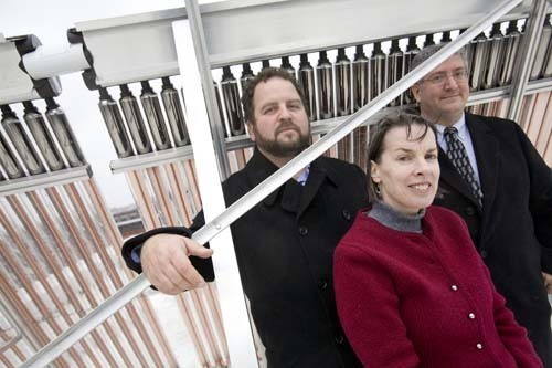 LET THE SUNSHINE IN: John Jacobson, left, Connie McGreavy and Mark DiPetrillo, members of the Rhode Island chapter of the U.S. Green Building Council, stand in front of a vacuum tube solar collector on top of Jacobson’s mixed-use building on Wolcott Street. / LET THE SUNSHINE IN: John Jacobson, left, Connie McGreavy and Mark DiPetrillo, members of the Rhode Island chapter of the U.S. Green Building Council, stand in front of a vacuum tube solar collector on top of Jacobson’s mixed-use building on Wolcott Street. /