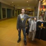 STEEL CURTAIN: Once surrounded by other shops, First Place Sports in Warwick&rsquo;s Rhode Island Mall now sits adjacent to gated vacant storefronts. Above, owner Frank Silva poses with gear he 
discounted in advance of the Super Bowl. / 