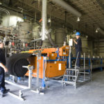 ASPEN AEROGELS operators Dave Lemire, forefront, and Justin Escobar work near the production line at the East Providence facility last July. / 