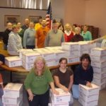 VOLUNTEERS FROM Bank Newport, OceanPoint Insurance Agency Inc. and American Legion Post 18 help pack 100 care packages for Rhode Island’s deployed troops at Bank Newport’s Turner Road location in Middletown. / 