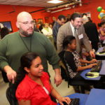 ANGELO GARCIA, (in green) executive director of the Ralph J. Holden Community Center, and Rep. Agostinho F. Silva, D-Central Falls, look on as children use computers donated to the new lab. / 