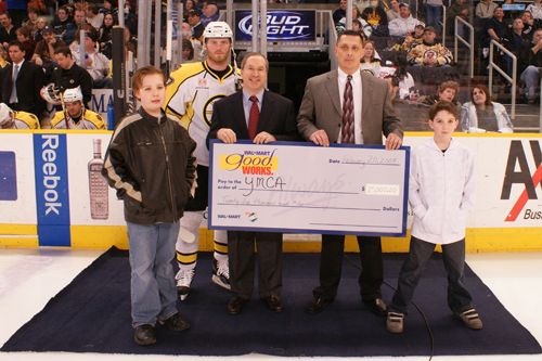 ALONGSIDE TWO YOUNG BRUINS FANS, Providence Wal-Mart store manager Martin Elizardo, right, holding check, presented David Devault, left, volunteer chair of the State Alliance of Rhode Island YMCAs, with a $25,000 grant check on the ice. Representing the Providence Bruins was the captain Jeremy Reich. / ALONGSIDE TWO YOUNG BRUINS FANS, Providence Wal-Mart store manager Martin Elizardo, right, holding check, presented David Devault, left, volunteer chair of the State Alliance of Rhode Island YMCAs, with a $25,000 grant check on the ice. Representing the Providence Bruins was the captain Jeremy Reich. /