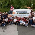 FEELING THE VIBE: Karl Wadensten, president of VIBCO, sits atop one of his company’s service vans. He is surrounded by VIBCO employees. / 