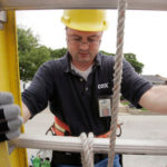 TUNED IN: Cox Communications technician William Hopkins climbs down a ladder during a pole installation in Warwick. / 