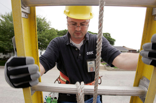 TUNED IN: Cox Communications technician William Hopkins climbs down a ladder during a pole installation in Warwick. / TUNED IN: Cox Communications technician William Hopkins climbs down a ladder during a pole installation in Warwick. /