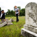 NEW LIFE: V. Darrell Waldron of the Rhode Island Indian Council examines toppled tombstones at the Locust Grove Cemetery with Amanda Hall. She is one of 14 people who will work this summer to help restore the run-down cemetery. / 