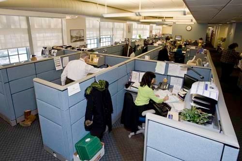PUTTING IN WORK: The Department of Labor and Training call center employees, shown above in February, work overtime and Sundays to eliminate the backlog. / PUTTING IN WORK: The Department of Labor and Training call center employees, shown above in February, work overtime and Sundays to eliminate the backlog. /