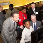 PROVIDENCE MAYOR David N. Cicilline, front left, and GTECH Regional Vice President Jay Gendron, front right, watch a student work with one of the new computers in the After School Advantage Lab at the Mt. Pleasant Library, as Councilman John J. Lombardi, back left, talks with a library patron. / 