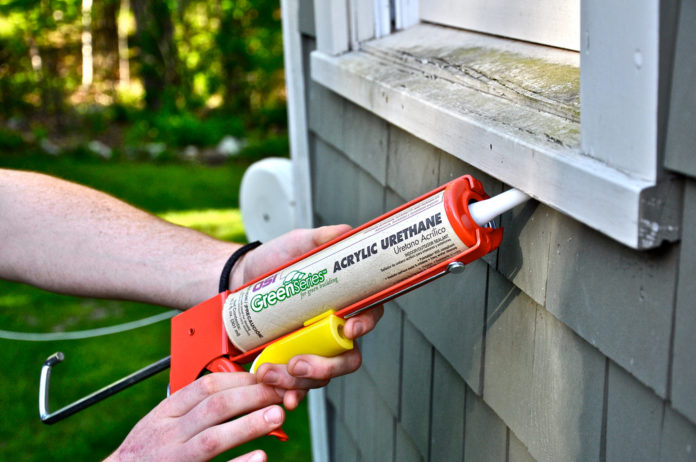 USING A CAULKING GUN, which can seal against air and water, is one way to weatherize a home. / USING A CAULKING GUN, which can seal against air and water, is one way to weatherize a home. /