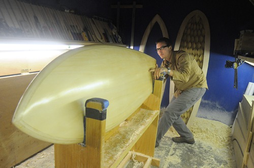 LOAN WOLF: Kevin Cunningham checks the line detail on a custom surfboard built at his Providence company, Spirare Surfboards. The startup was a recent recipient of an EDC micro-loan. / LOAN WOLF: Kevin Cunningham checks the line detail on a custom surfboard built at his Providence company, Spirare Surfboards. The startup was a recent recipient of an EDC micro-loan. /