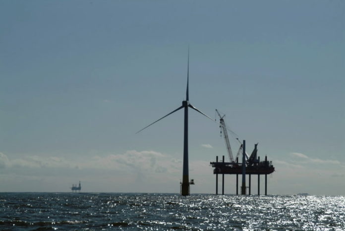 AN INSTALLATION VESSEL erects an offshore wind turbine in waters off the United Kingdom last summer. Deepwater Wind hopes to do the same off Rhode Island. / 