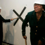 Dr. Edward J. Wing, dean of medicine at The Warren Alpert Medical School at Brown University, takes a swing with a sledgehammer as Brown President Ruth J. Simmons prepares for her turn during a groundbreaking for the medical school’s planned home at 222 Richmond St. in Providence last week. / 