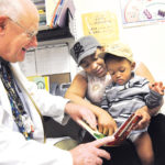 COMMUNITY SPIRIT: Dr. John Moran with 1-year-old Giovani Andrade and his mother, Kim Andrade, at the Allen Berry Health Center. / 