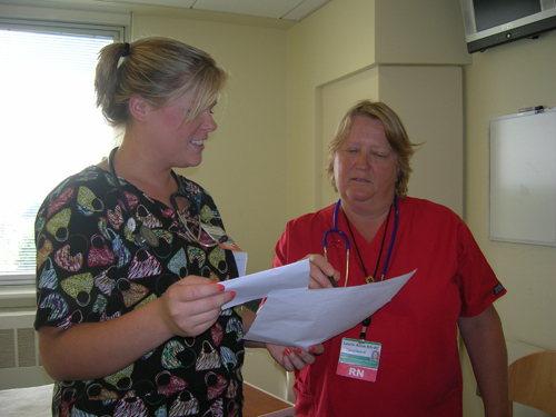 HANDING OFF: Nurses Ara Millette, left, and Laurie Allan review a patient’s information during a shift change at Newport Hospital. / HANDING OFF: Nurses Ara Millette, left, and Laurie Allan review a patient’s information during a shift change at Newport Hospital. /