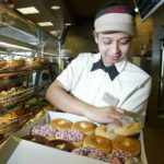 A TIM HORTONS EMPLOYEE fills a customer's order. The fourth largest publicly-traded restaurant chain in North America said Wednesday it will close all of its Providence and Hartford restaurants. / 