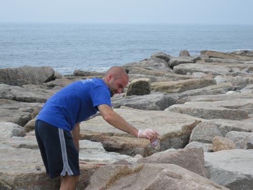 DOING THEIR PART: Chris Cullion, an employee with DiSanto Priest & Co., picks up a piece of trash during a Save The Bay cleanup last year. The company encourages its employees to help with beach cleanups. / DOING THEIR PART: Chris Cullion, an employee with DiSanto Priest & Co., picks up a piece of trash during a Save The Bay cleanup last year. The company encourages its employees to help with beach cleanups. /