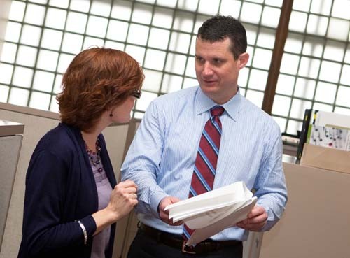 BAY WATCH: Sean F. Murphy, chief financial officer at Narragansett Bay Insurance Co., speaks with senior accountant Donna Rizardini. He leads compliance efforts for state regulations in Rhode Island, Massachusetts, New Jersey and New York. / BAY WATCH: Sean F. Murphy, chief financial officer at Narragansett Bay Insurance Co., speaks with senior accountant Donna Rizardini. He leads compliance efforts for state regulations in Rhode Island, Massachusetts, New Jersey and New York. /