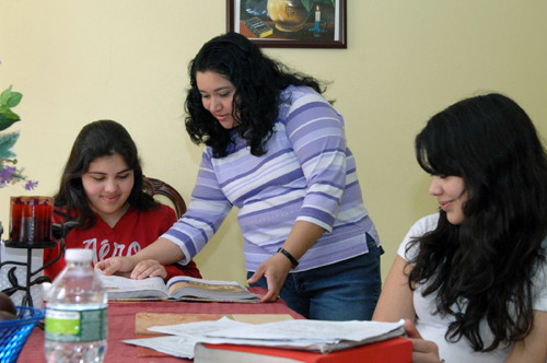 BRUSHING UP: Claudia Santamaria, standing, helps her daughters with their homework. Santamaria is enrolled in a RIC and DLT skill-development course that begins this week. / BRUSHING UP: Claudia Santamaria, standing, helps her daughters with their homework. Santamaria is enrolled in a RIC and DLT skill-development course that begins this week. /