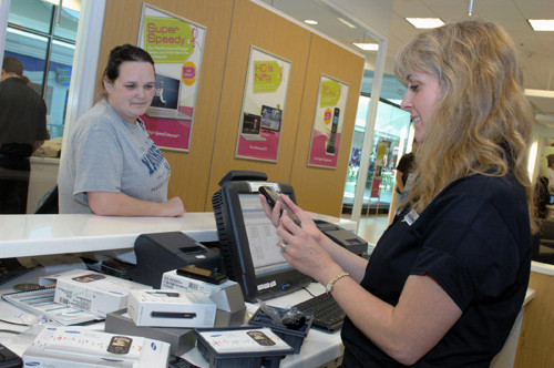 WITH THE PROGRAM: Amanda Flynn, left, waits as Cox employee Kerri Periera
programs her new cellphone at the Solutions Store at Warwick Mall. / WITH THE PROGRAM: Amanda Flynn, left, waits as Cox employee Kerri Periera
programs her new cellphone at the Solutions Store at Warwick Mall. /