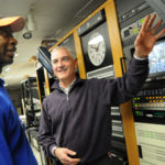 AIR TIME: David Piccerelli, right, president and CEO of Rhode Island PBS, speaks with a tech in the station’s systems room at its Providence studio. / 