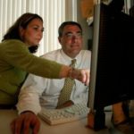 GAINING AN EDGE: Jeff Meyer, director of information systems for Neighborhood Health Plan of Rhode Island, and Shirley Lopes, clinical coordinator, look through some files on the HealthEdge software. / PBN PHOTO/MICHAEL PERSSON