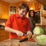 EATING WELL: Eleven-year-old Ryan Morel makes a salad while his mother, Dana, looks on. Ryan dropped from size 16 to size 12 through diet. / PBN PHOTO/DAVID LEVESQUE