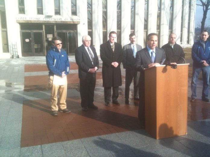 U.S. Rep. David N. Cicilline speaks in front of R.I. Department of Health offices. Behind him, from left: Dan Couture, John C. Gregory, president and CEO of the Northern Rhode Island Chamber of Commerce, Woonsocket Mayor Leo T. Fontaine,  and UNAP general counsel Christopher Callaci. / PHOTO COURTESY RICHARD ASINOF