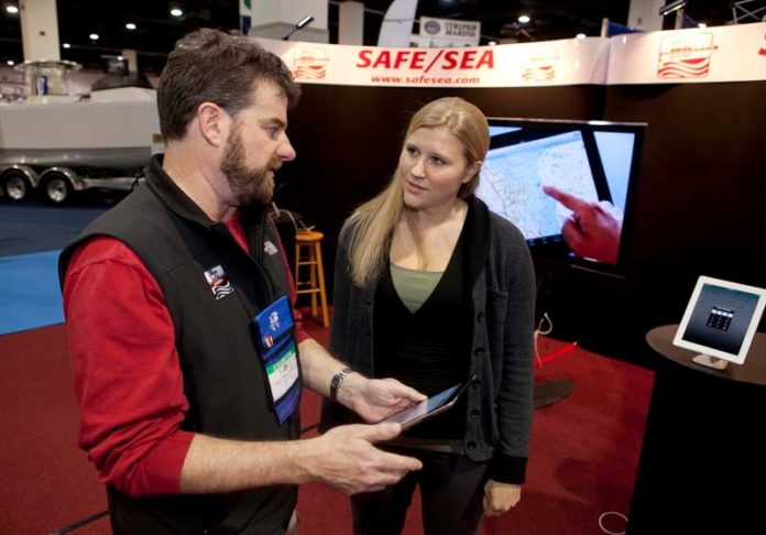 STAYING AFLOAT: Pete Andrews, vice president at Safe/Sea, describes the company's iPad application to Christina Hopper at the R.I. Boat Show in January. / PBN PHOTO/DAVID LEVESQUE